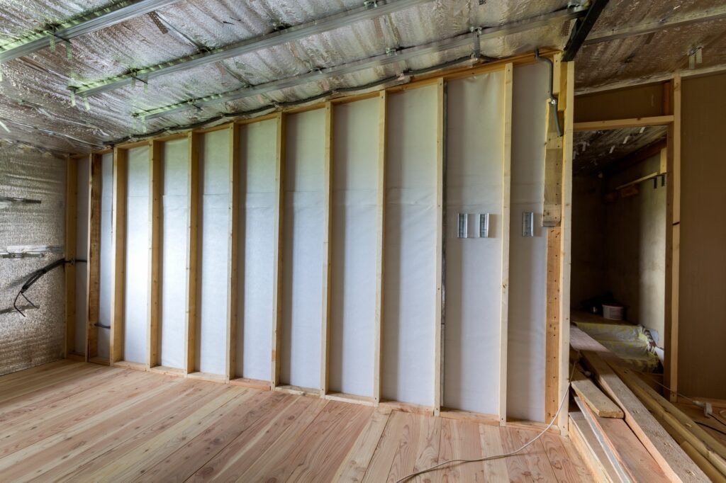 Room under construction and renovation with silver aluminum foil on walls and ceiling, oak floor and